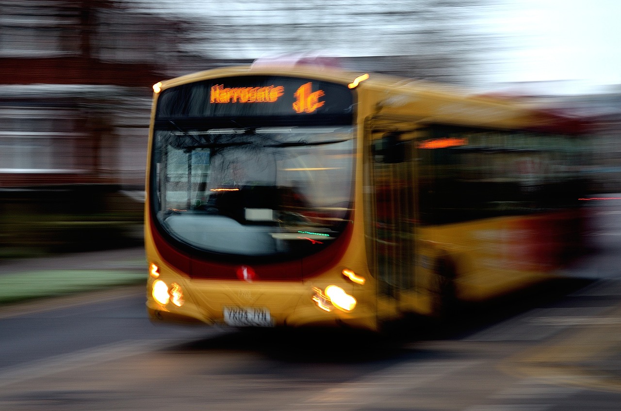 Photo of a bus moving fast. The bus is yellow and says it is going to Harrogate on the front.