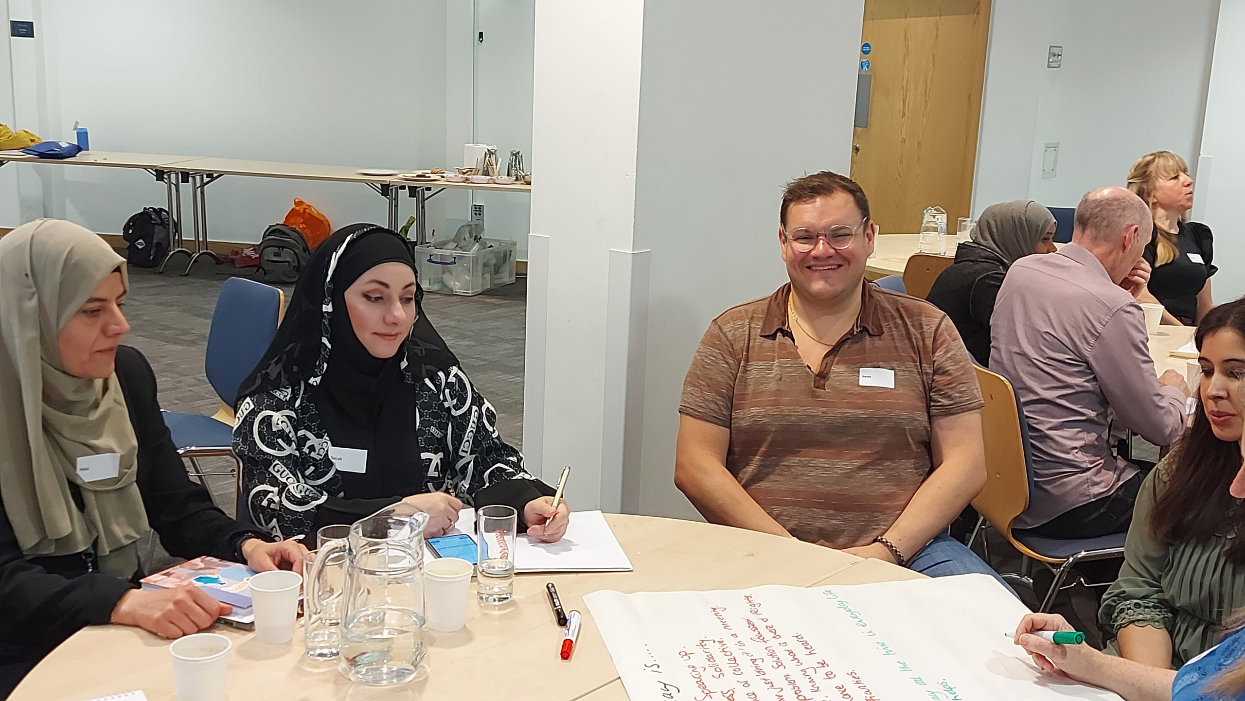 A photo from our Advocacy Together event. There are four people sat at a round table, which has some paper, pens and water glasses on top of it.