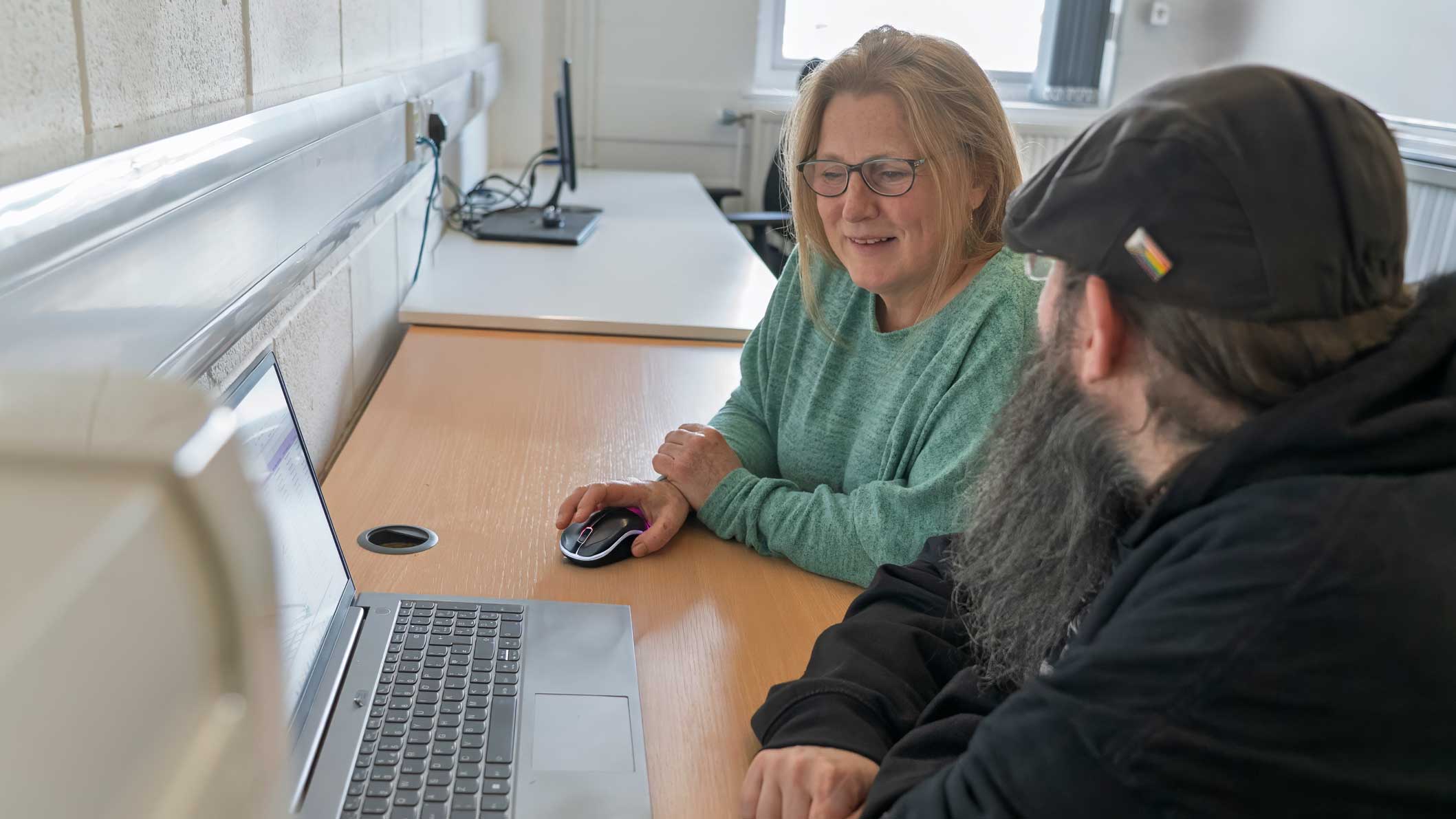 A photo of two members of our staff team looking at a laptop and discussing what's on the screen.