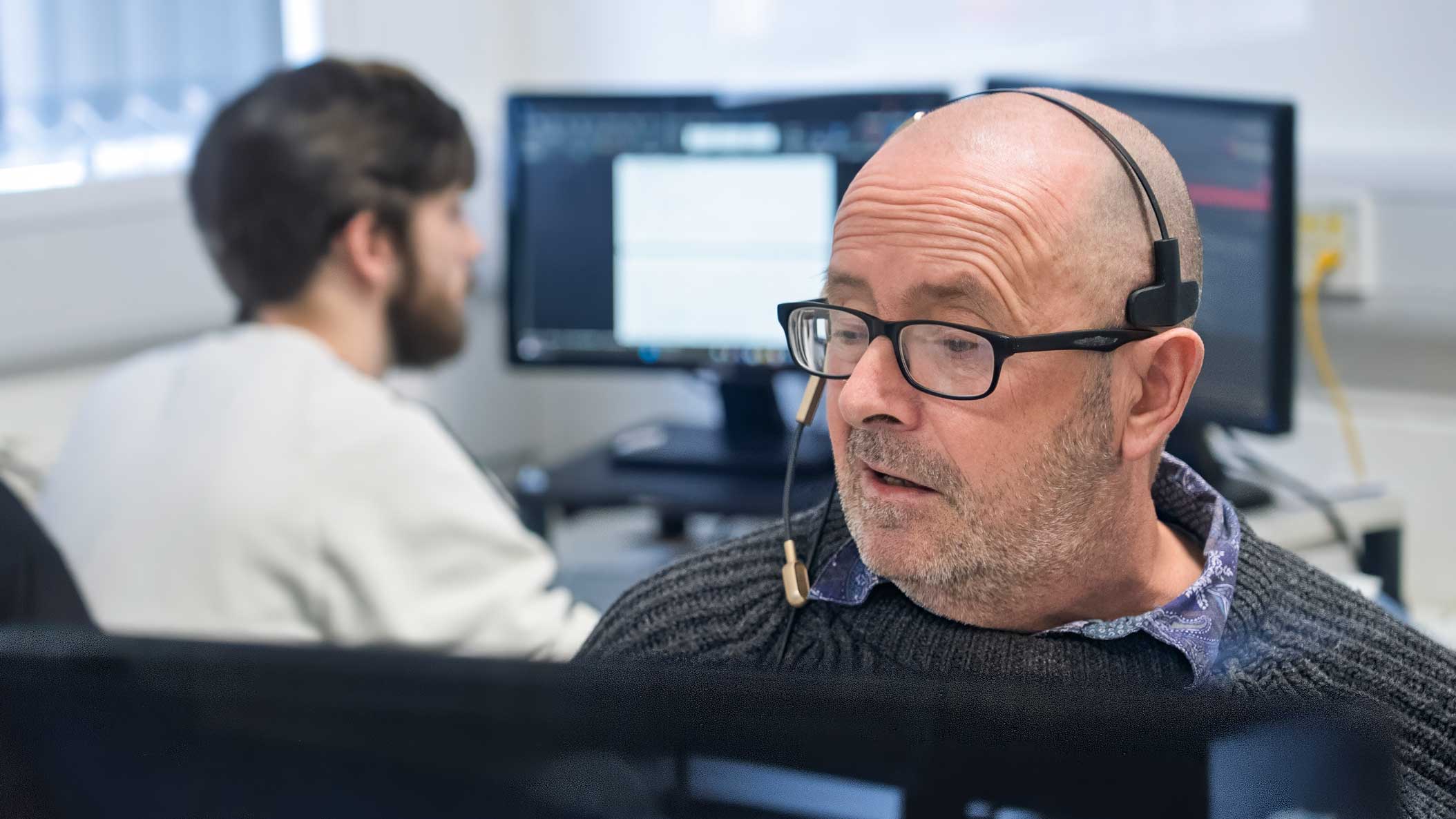 A photo of our First Contact Team (FCT), answering phone calls via their headsets whilst sat at their desks in our office.
