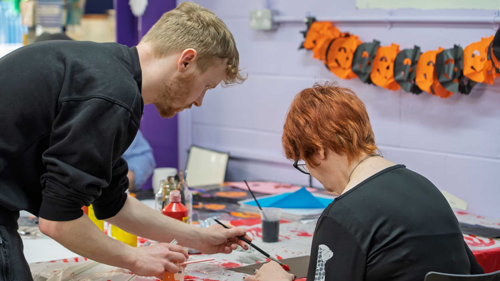 A photo of Charlie, one of our Support Workers, helping a member of our Learning Disability Day Opportunities service with an activity