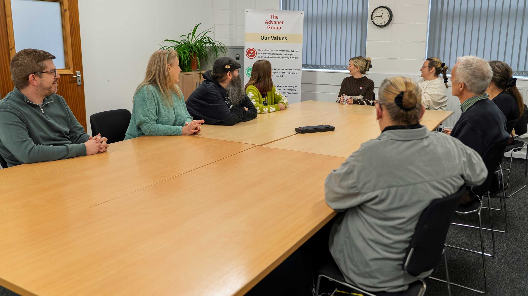 A photo of members of our staff team in a meeting, talking about our values.