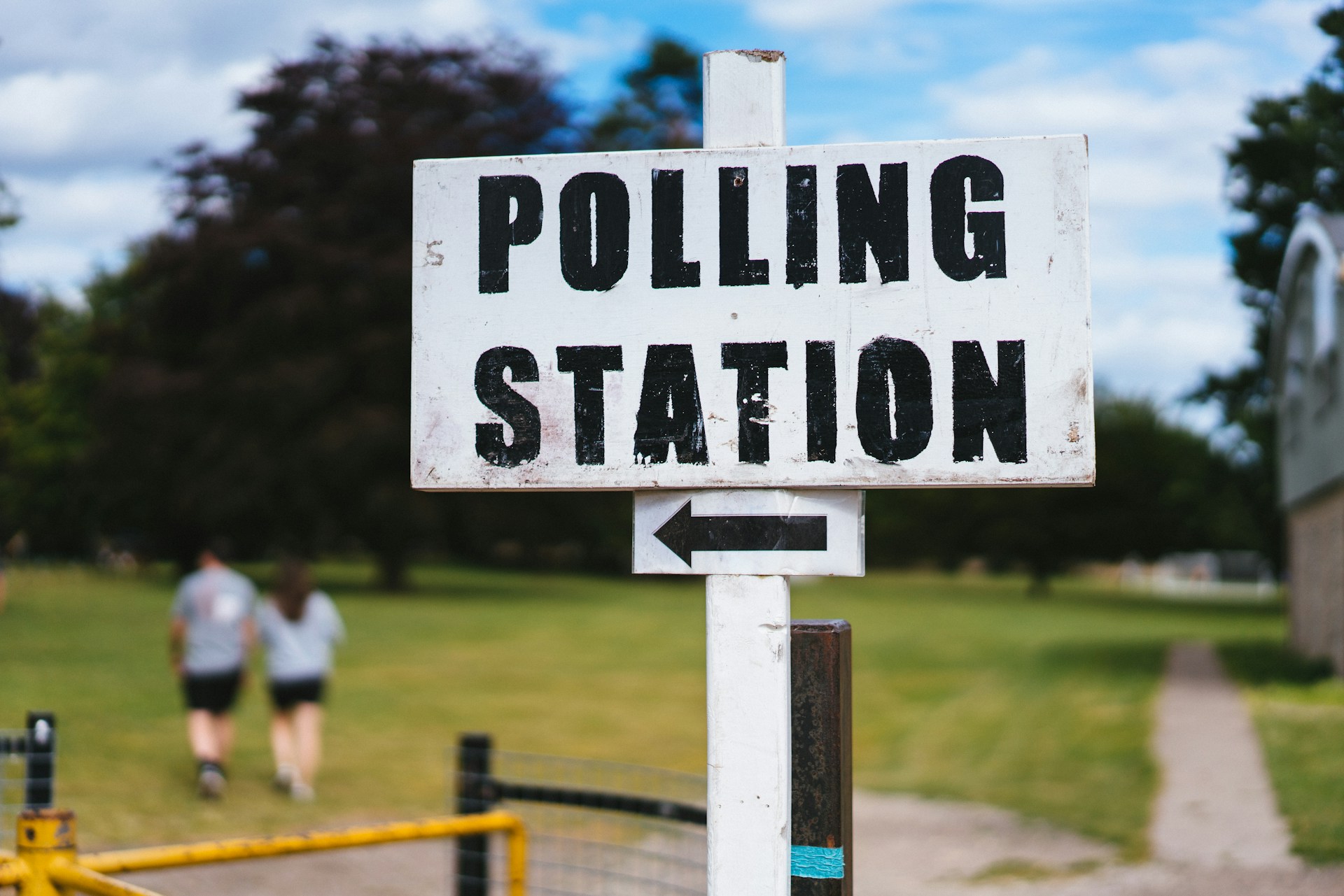 A photo of a wooden sign pointing west towards a polling station